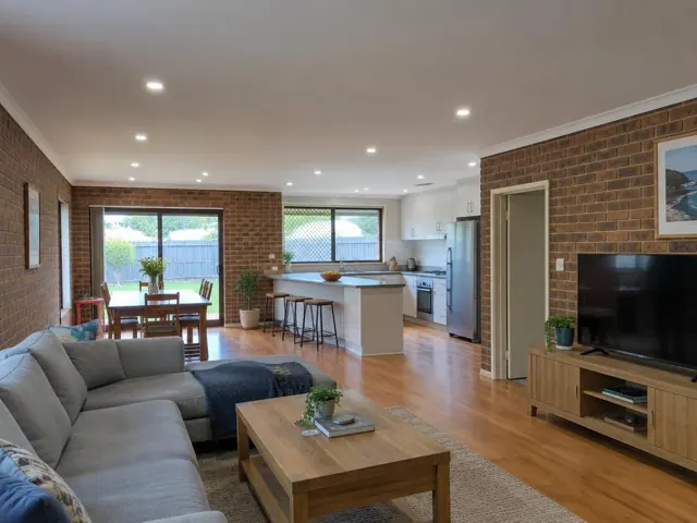 Open-plan living room, dining area and kitchen with recessed downlights in a brick home in Blacksmiths